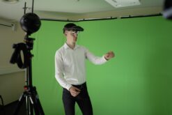 Person steht vor Greenscreen mit AR-Brille