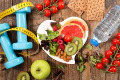 Ein Tisch mit Hanteln und Maßband, Wasserflasche, Obst und Gemüse und Knäckebrot
