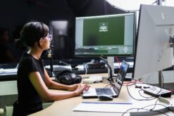 Frau sitzt im Studio und schneidet ein Video am PC