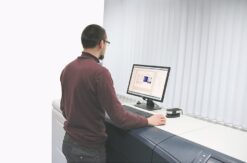 Mann steht am Monitor im Druckzentrum.