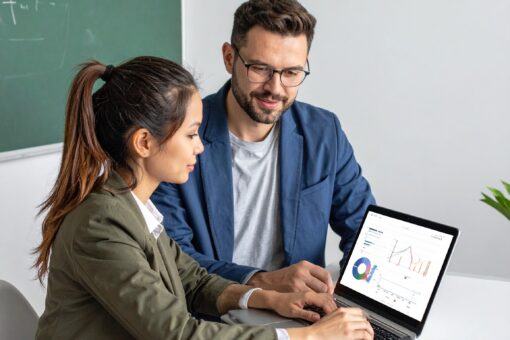 Student und Mentorin sitzen vor einem Laptop mit Statistiksoftware