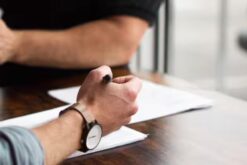 Hand hält einen Stift über einem Blatt Papier.
